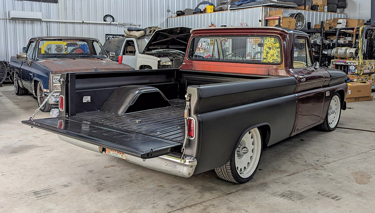 A black and orange 1966 Chevy C10 truck in a mechanic's garage