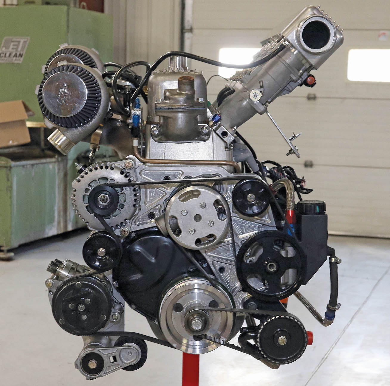 The front drive is an incredible combination of components, practically none of which were originally designed to work with the Chevrolet straight-six. Johnson’s came up with a billet machined front plate to give a mounting point for everything. The water pump is for a BMW, chosen for its efficiency and small size. On the driver side at the bottom is the external oil pump.