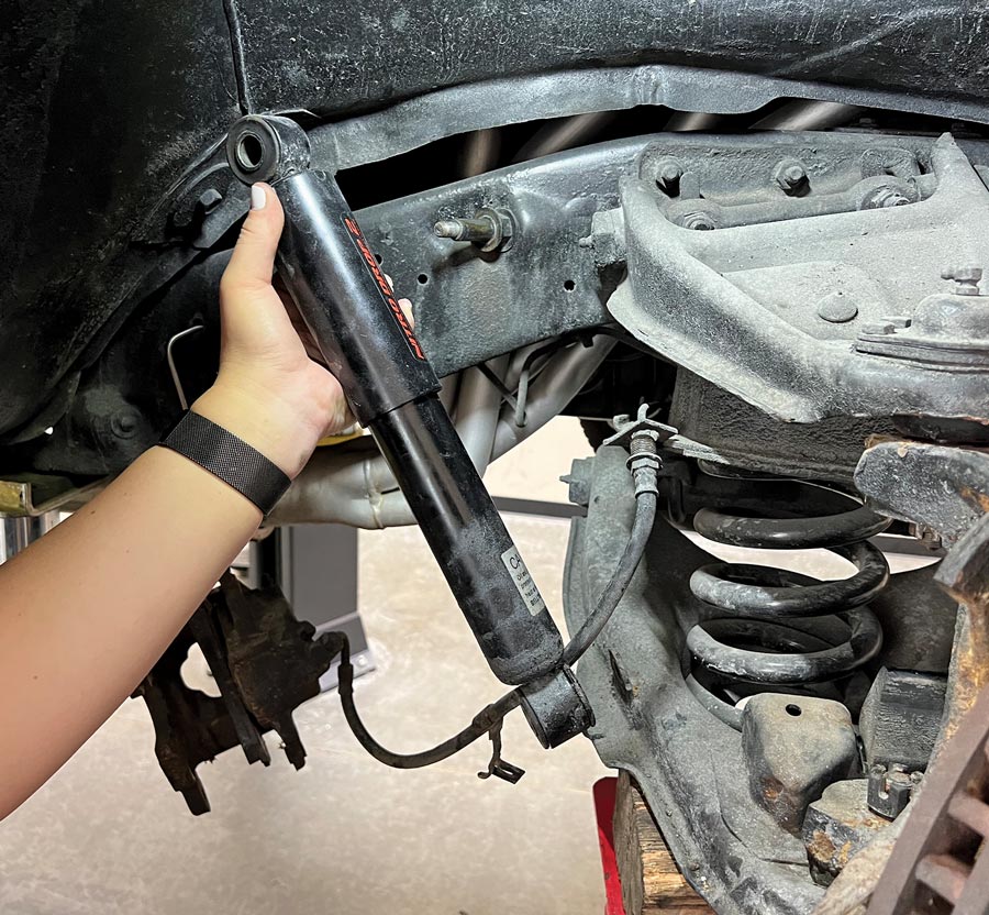 a hand holds a freshly removed shock absorber