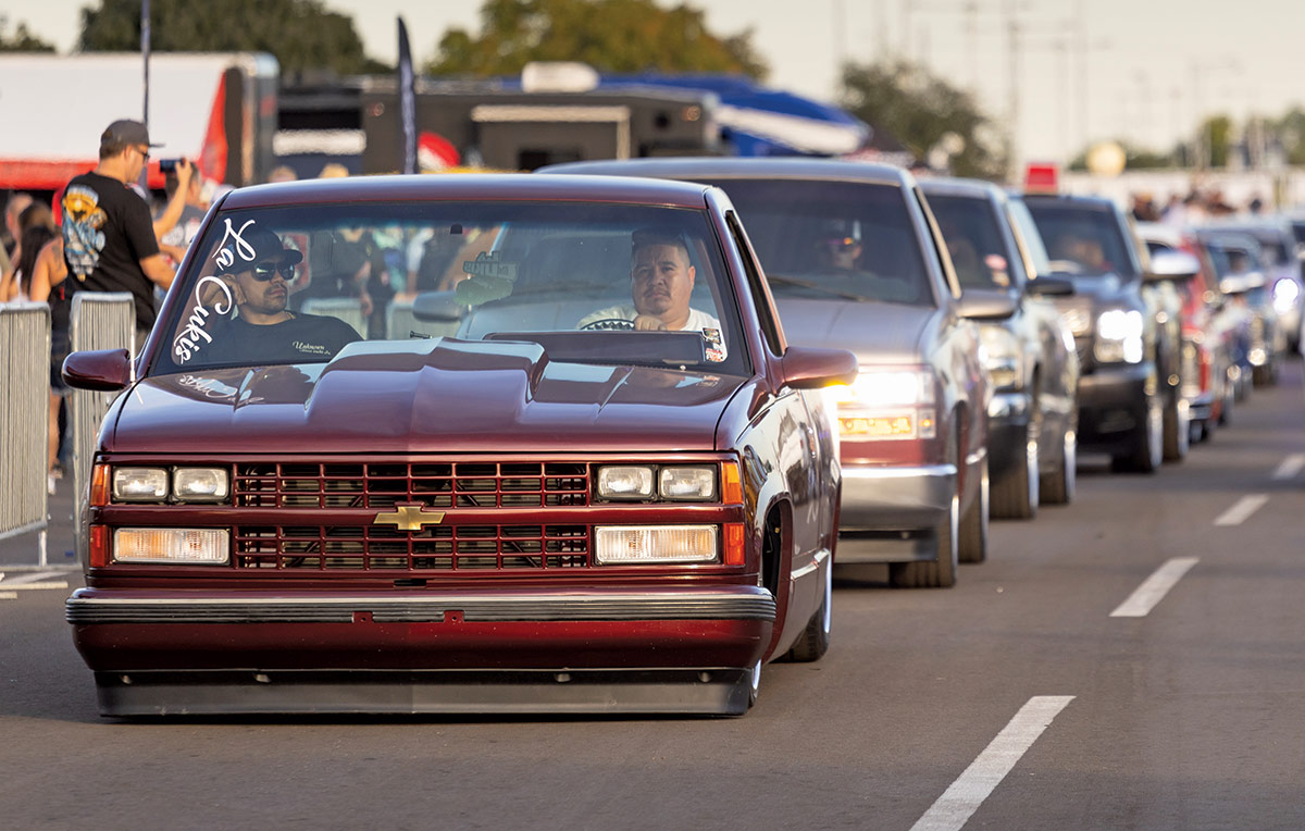 Close-up landscape photograph view of several different colored Chevrolet vintage truck vehicles in the same row formation driving away