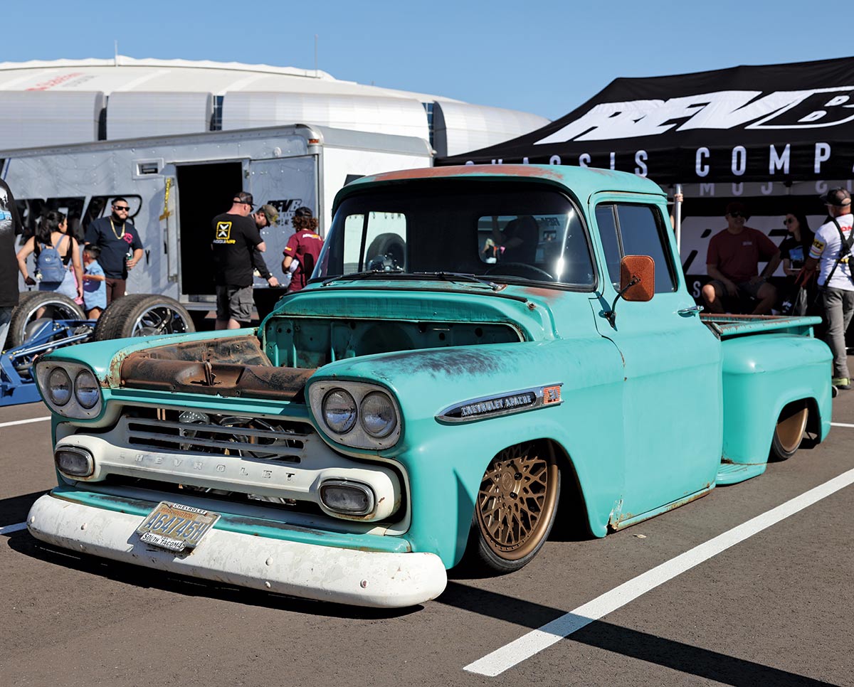Close-up landscape photograph view of a bright turquoise colored Chevrolet 31 Apache vintage truck vehicle that has its front hood entirely exposed as the car is parked in a parking lot space