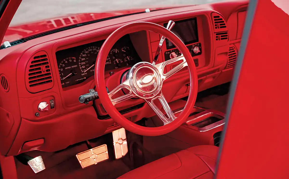 close up view of cherry red '98 Chevy wheel and dashboard