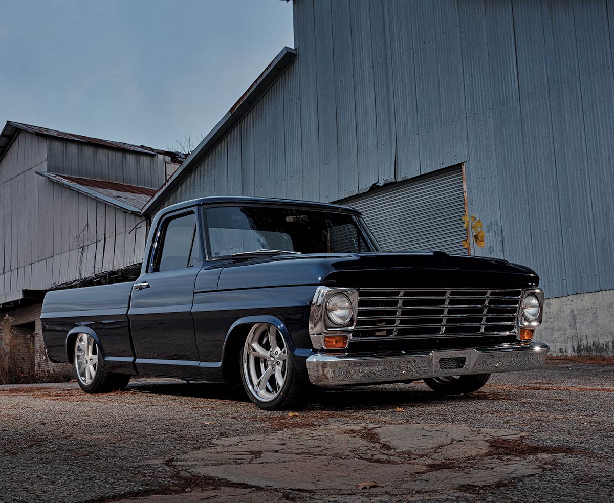 Portrait close-up angle photo view of a black 1967 Ford F100 vintage vehicle parked outside nearby some industrial buildings
