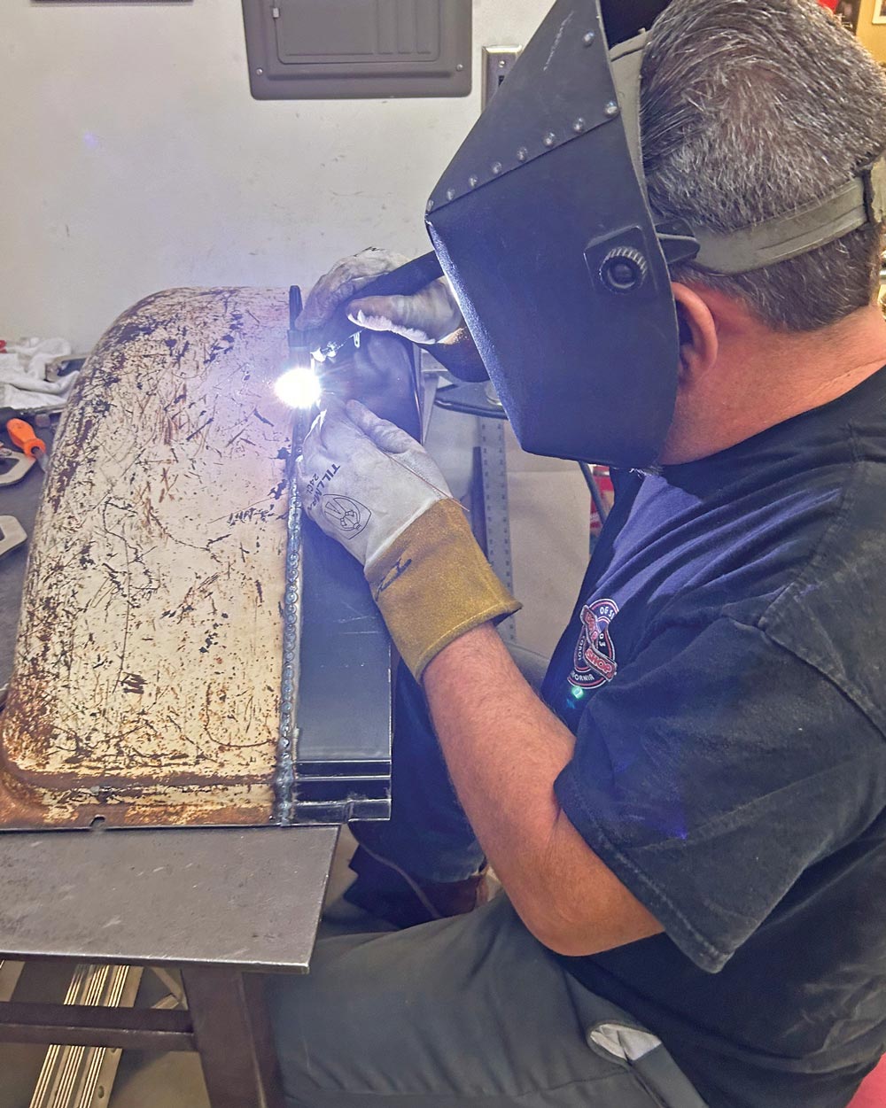 man welding portion of truck bed