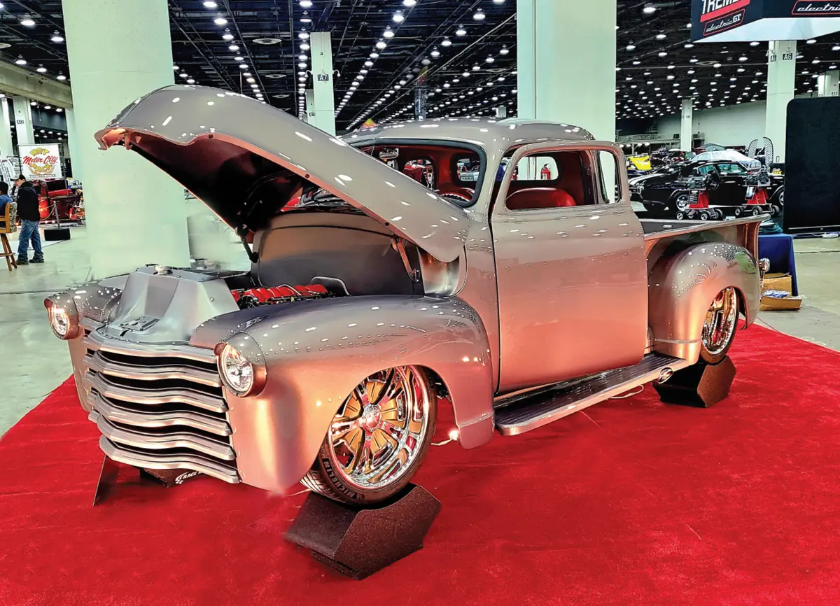 driver side quarter view of a grey classic truck with its hood propped open