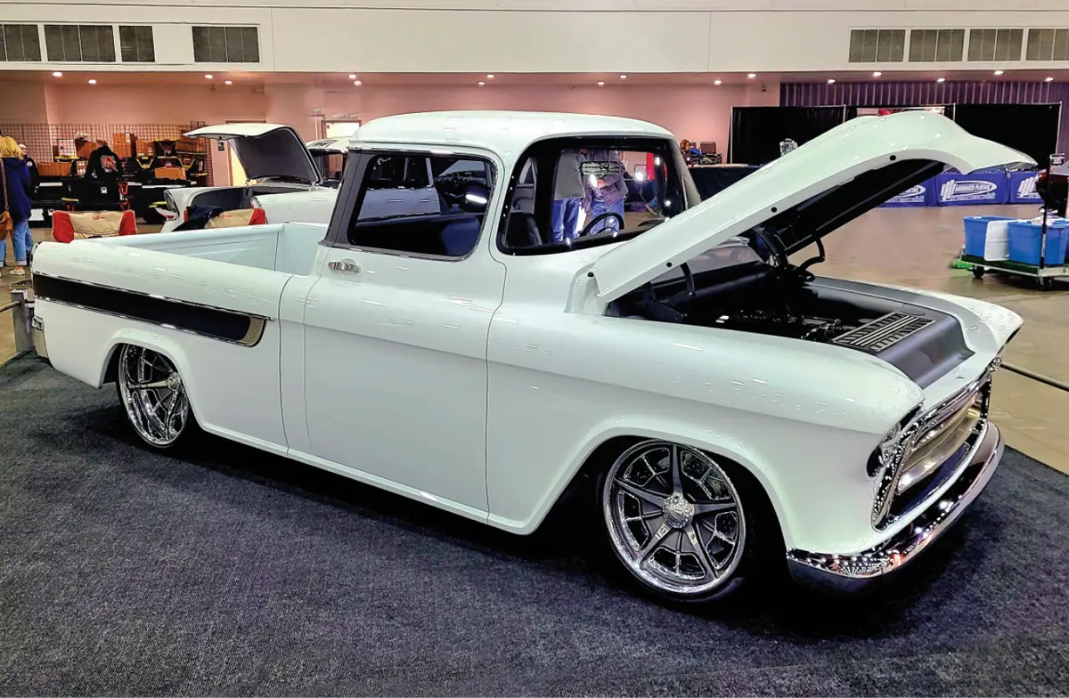 passenger side quarter view of a white classic truck with its hood propped open