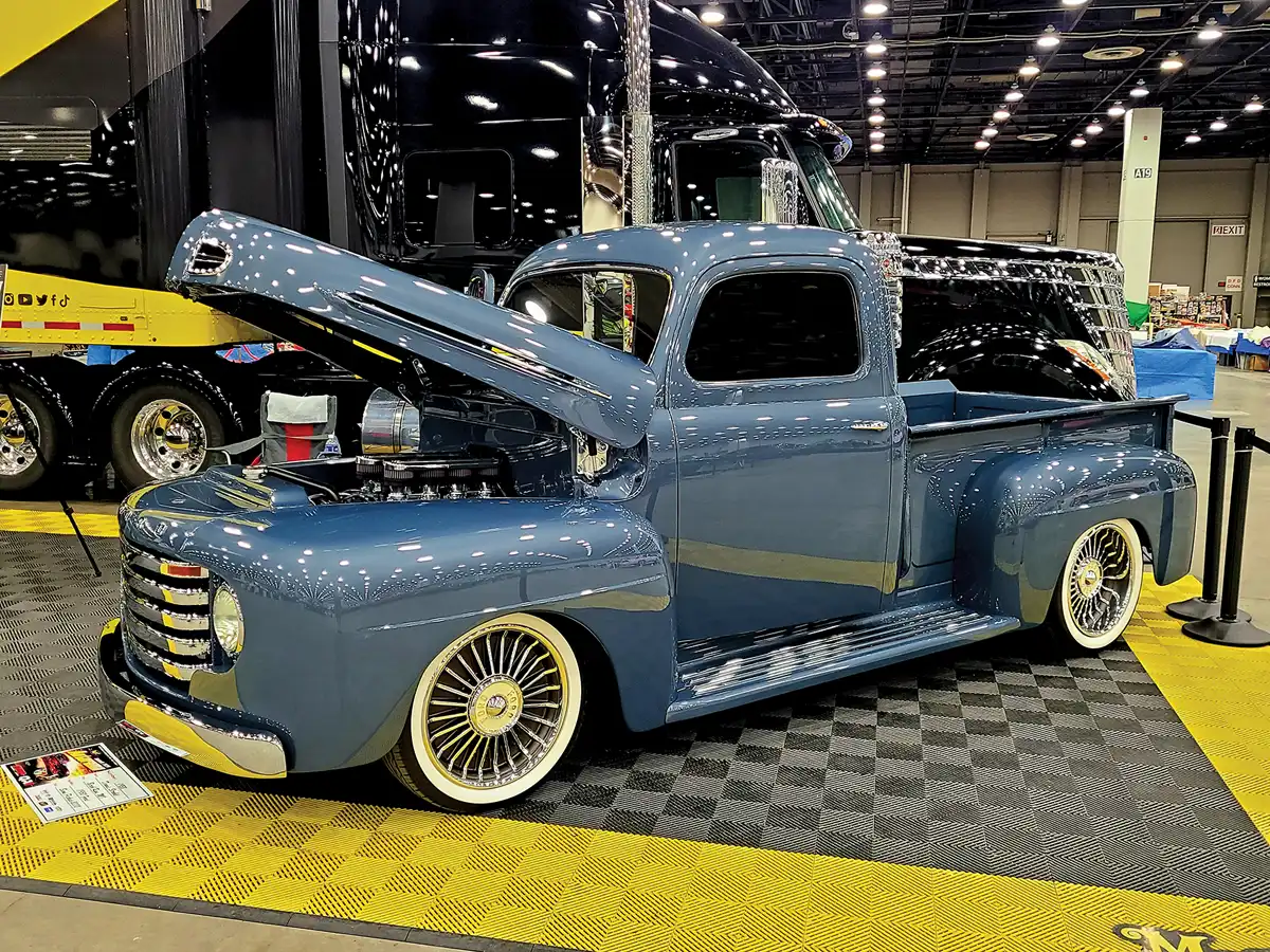 driver side quarter view of a metallic slate blue classic truck with its hood propped open