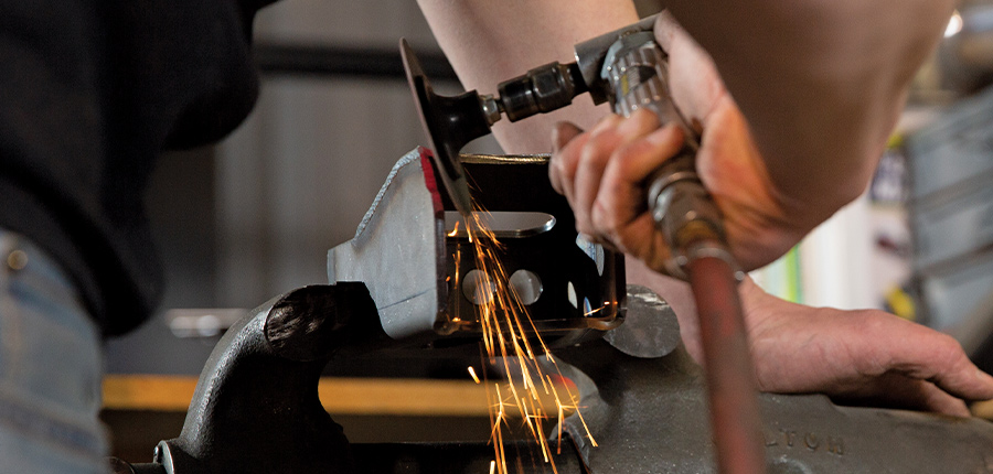 closeup of person using a hand saw to trim a piece of the bracket