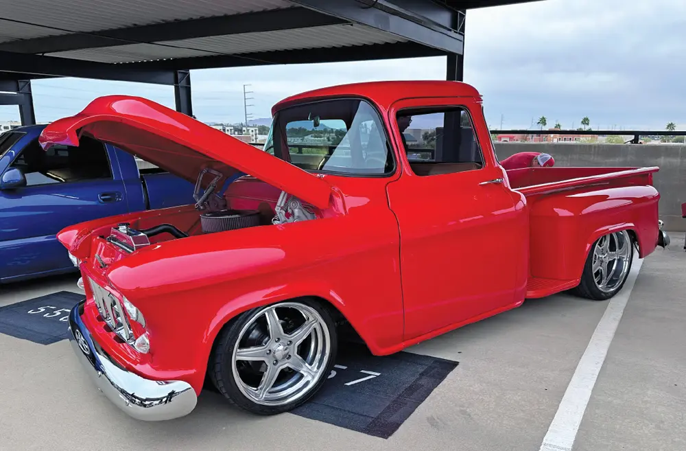 quarter driver side view of a vibrant red classic truck with its hood propped open
