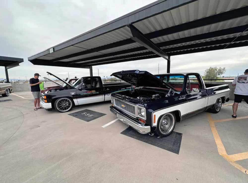 a retro black and white classic truck with its hood propped open parked beside another black and white truck with graphics at the 2024 Reunion Truck Show