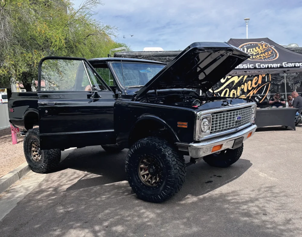 passenger side of a black truck with all terrain tires and its hood and passenger side door open