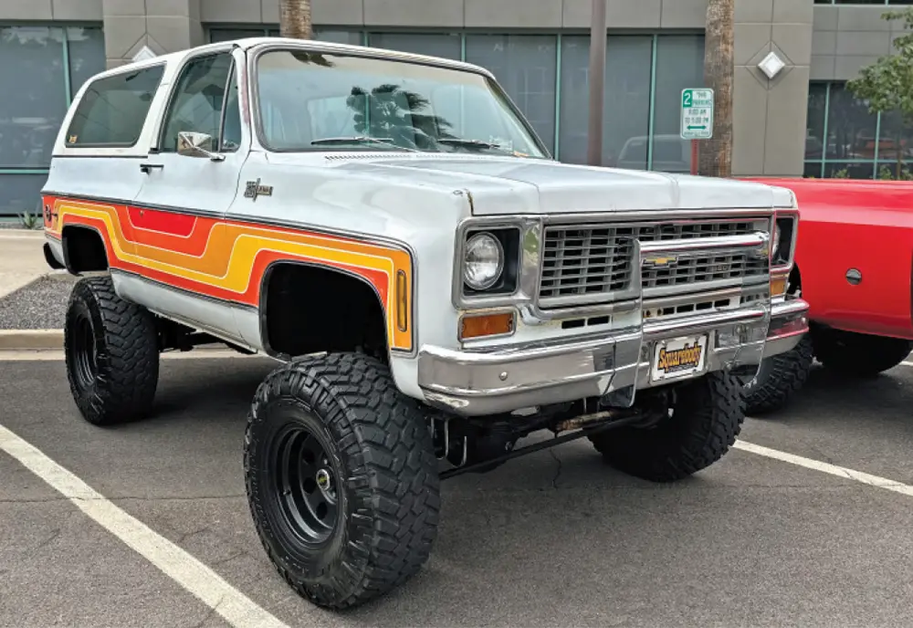 quarter passenger side of a retro white and red/orange/yellow graphic Chevy Blazer with all terrain tires