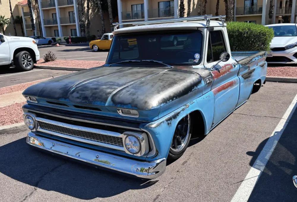 quarter driver side of a bright blue, black and patina lowriding classic truck
