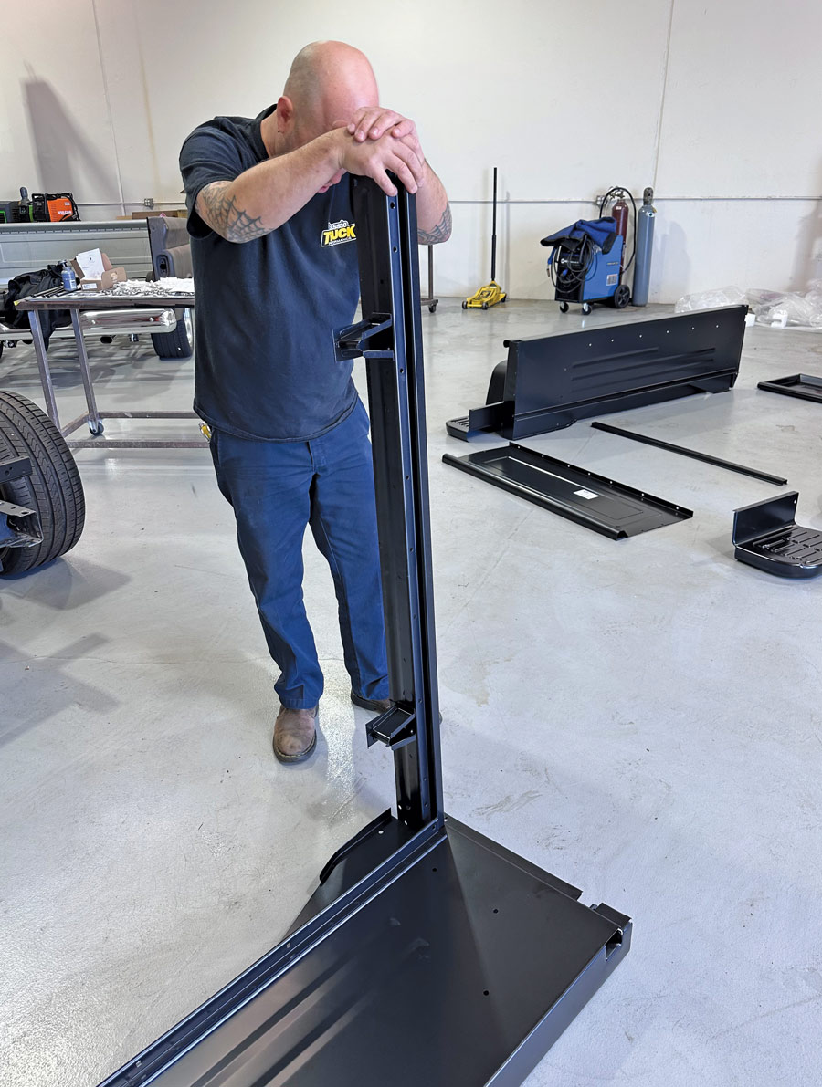 man standing up while holding a truck bed piece in place
