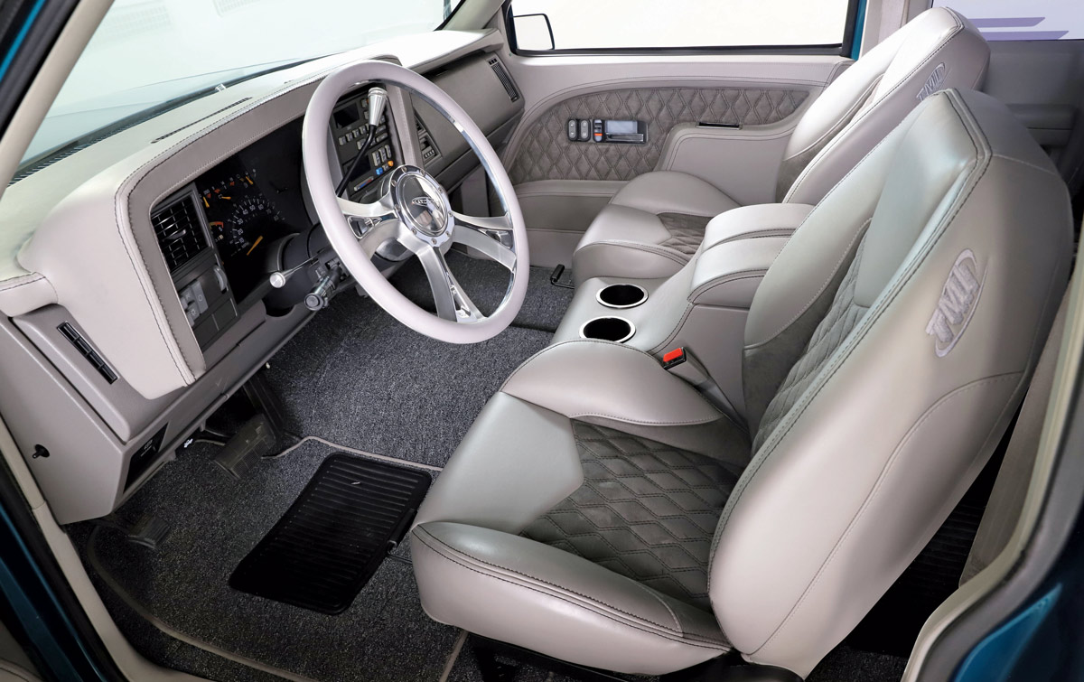 Custom gray and white interior of a 1990 Chevrolet C1500, featuring diamond-stitched upholstery and modern steering wheel