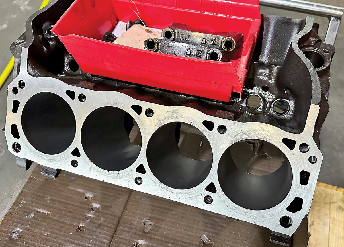 Machined engine block with a red container holding various hardware components on top