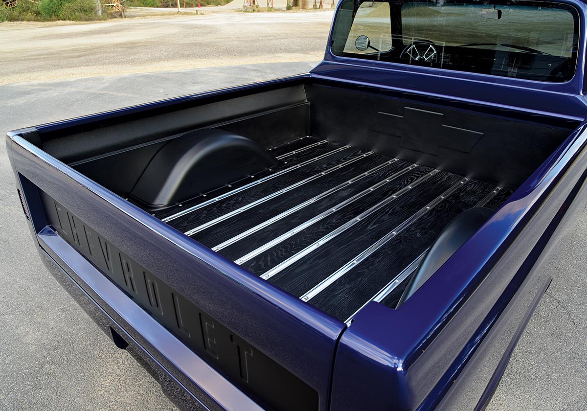 The bed of a 1966 Chevrolet C10, featuring polished wooden slats and a clean, custom-finished interior