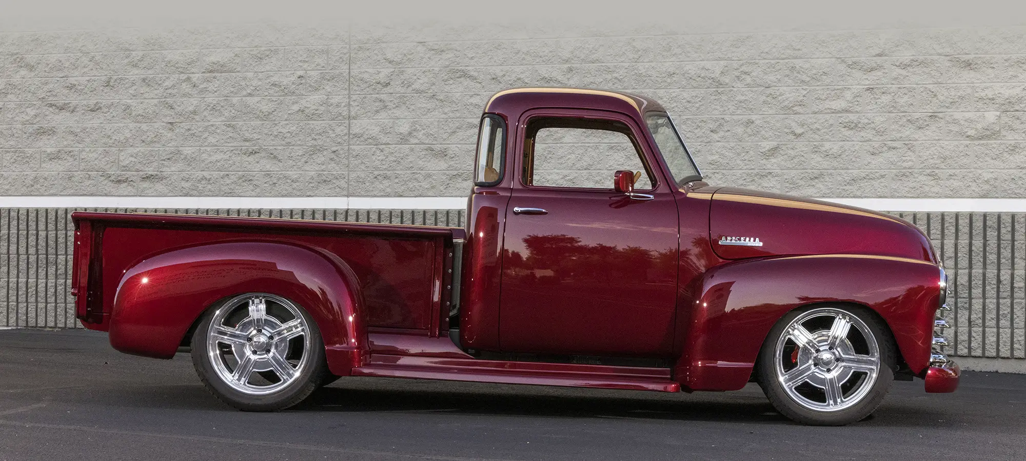 Side profile of a 1952 Chevrolet 3100, red custom build, chrome accents, lowered stance