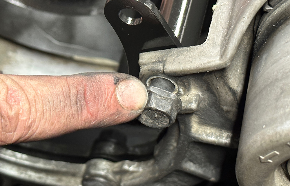 Pointing out a specific mounting bolt location on the compressor bracket of a 1990s Chevrolet CK 1500
