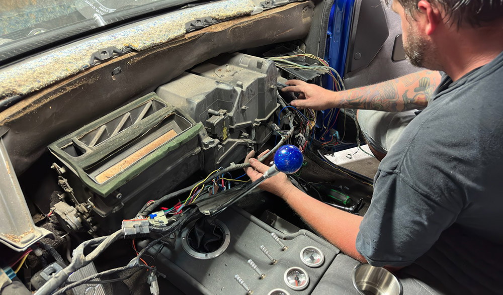 Inspecting the wiring and air duct connections behind the dashboard of a 1990s Chevrolet CK 1500