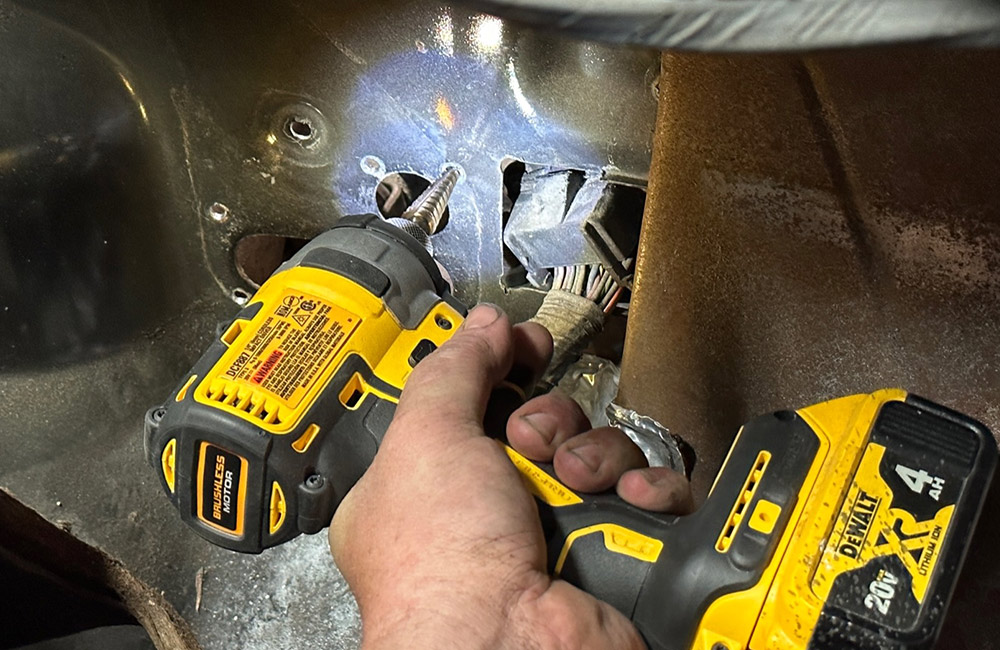 Drilling holes to fit the new air conditioning system into a 1990s Chevrolet CK 1500 firewall