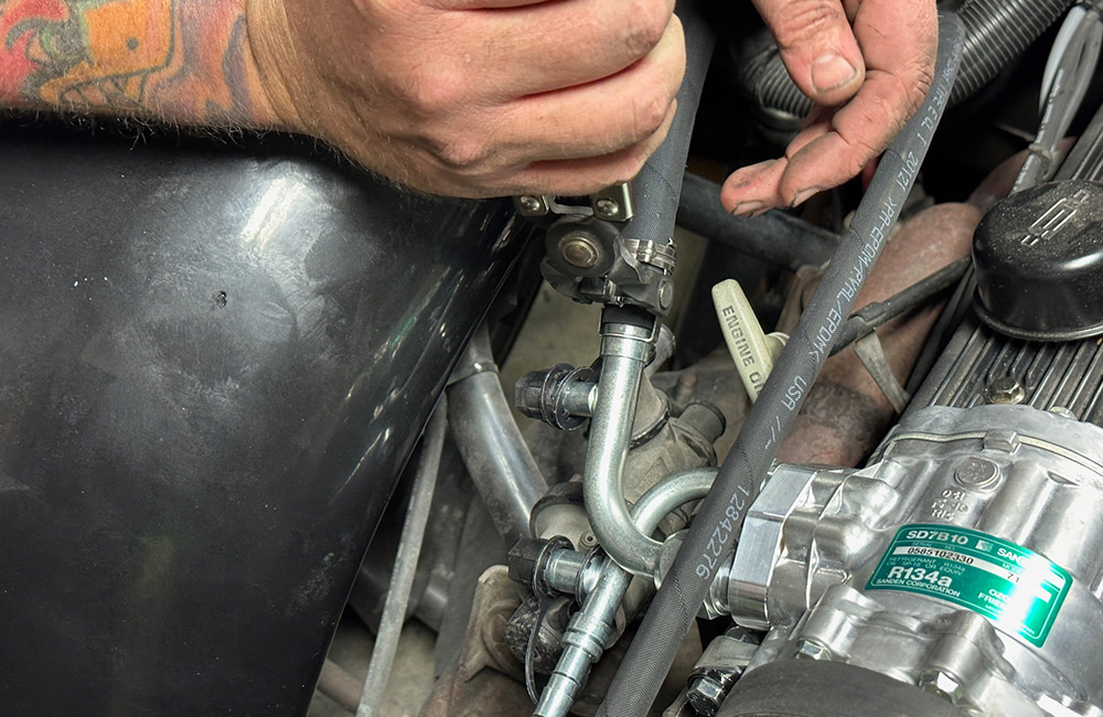 Attaching an AC hose to the compressor in a 1990s Chevrolet CK 1500 engine bay