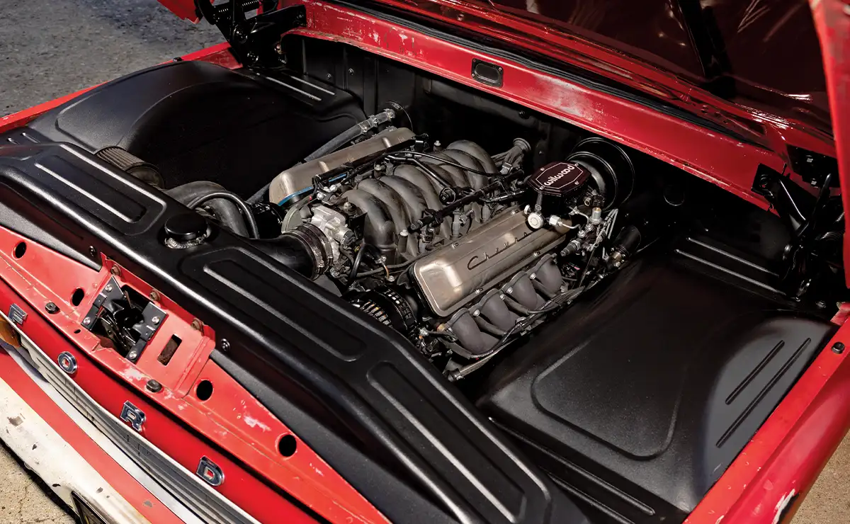 Under the hood of the Ford F-100, a neatly installed Chevy LS engine setup with custom black panels and Wilwood parts