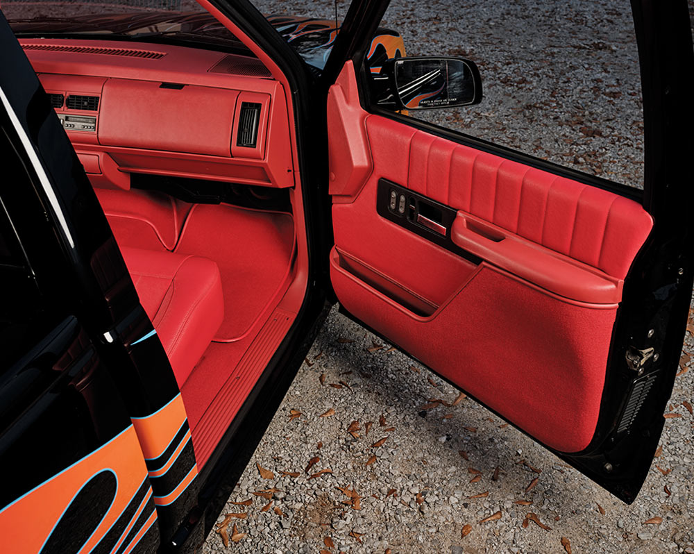 Full view of the red leather bench seat and interior of a custom GMC Sierra
