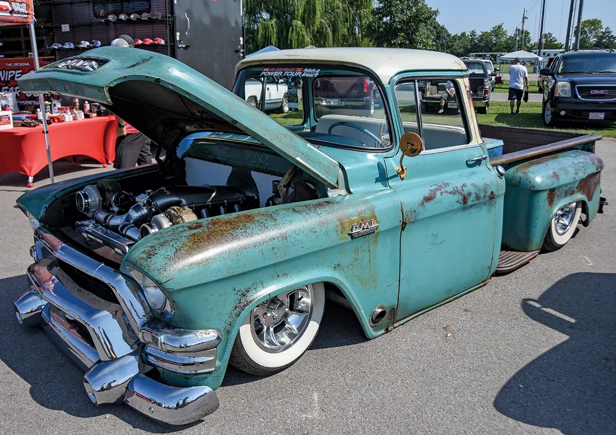 1957 GMC 100 pickup with a patina finish, showcasing a dual-turbocharged engine and whitewall tires