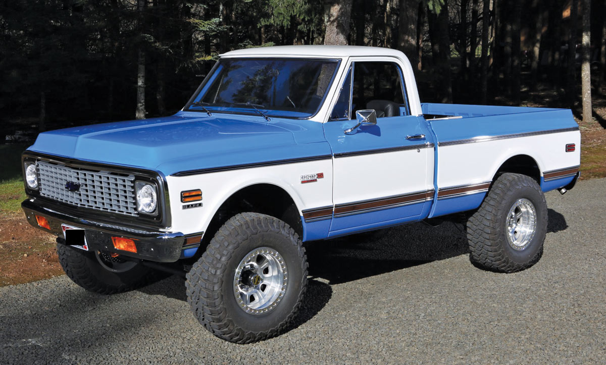 Lifted blue and white Chevy K10 with large off-road tires and a chrome grille