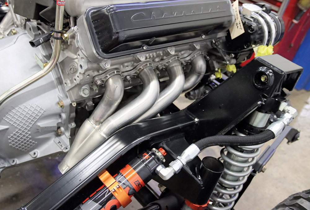 Engine bay of a Chevy K10 with a high-performance engine, headers, and coil-over suspension