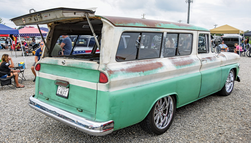 vintage green and white Suburban with patina and lowered stance at a car event