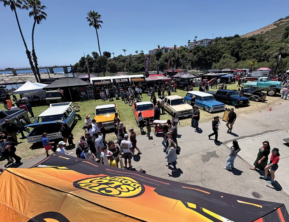 Classic truck show by the coast, featuring various custom trucks and a lively crowd