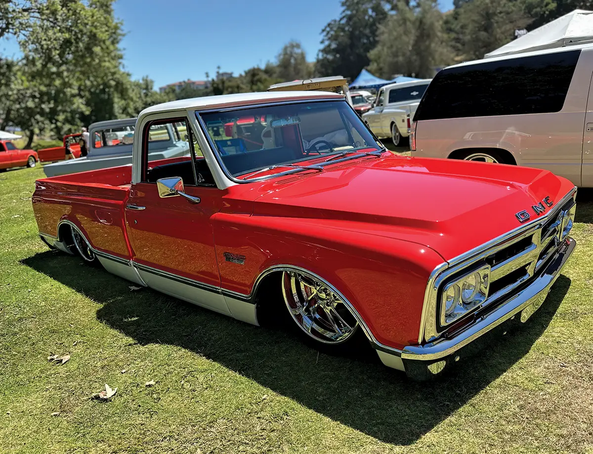 Bright red GMC truck with a lowered stance and chrome details at a car show