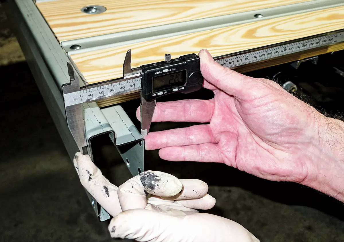 Using calipers to measure metal trim thickness on the truck bed