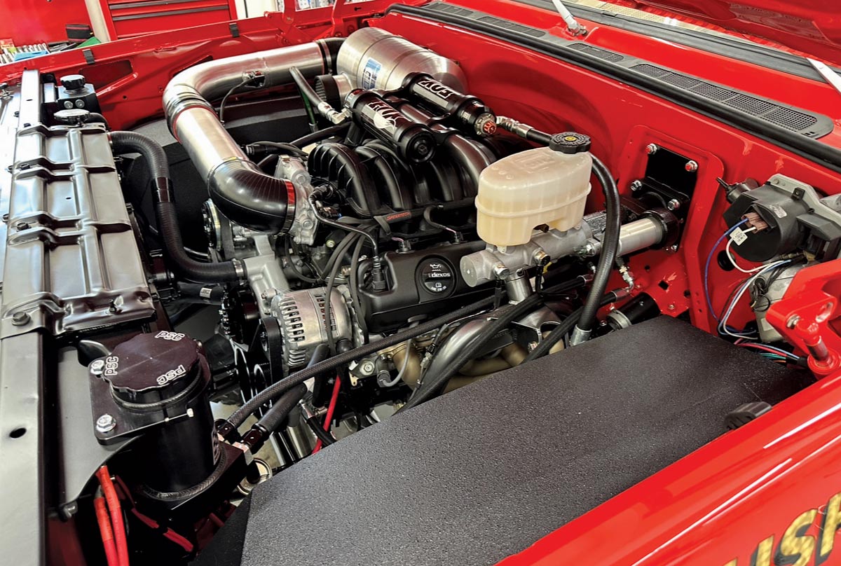 Engine bay of GMC K2500, featuring modern LS engine with dual PSC reservoirs and polished intake