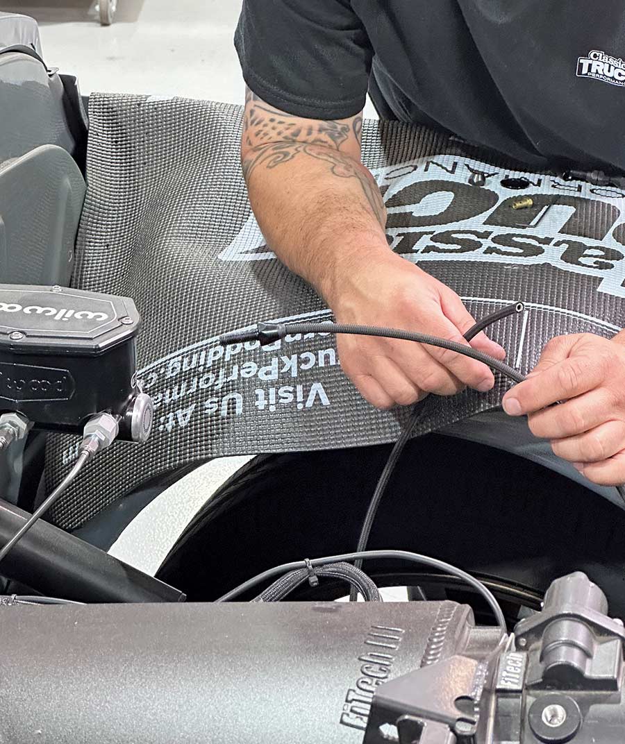 Technician routing Lokar throttle cable through the engine bay for optimal positioning