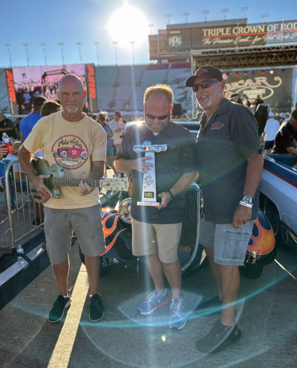 proud award recipients with their classic flame-painted Ford truck at the Triple Crown Truck Show