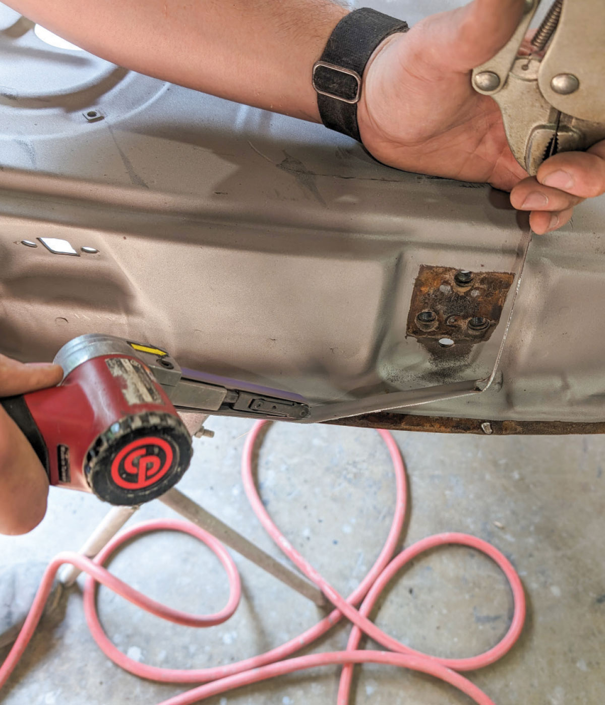 Pneumatic tool trimming 1966 Chevy truck door panel with vise grip holding alignment