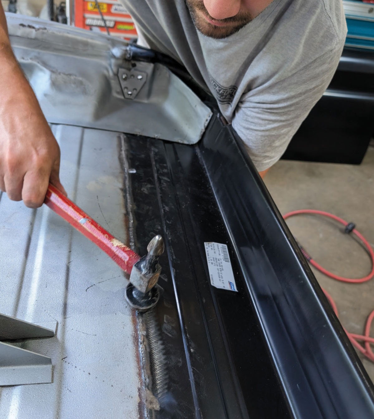 Technician hammering welds smooth on 1966 Chevy truck door inner seam