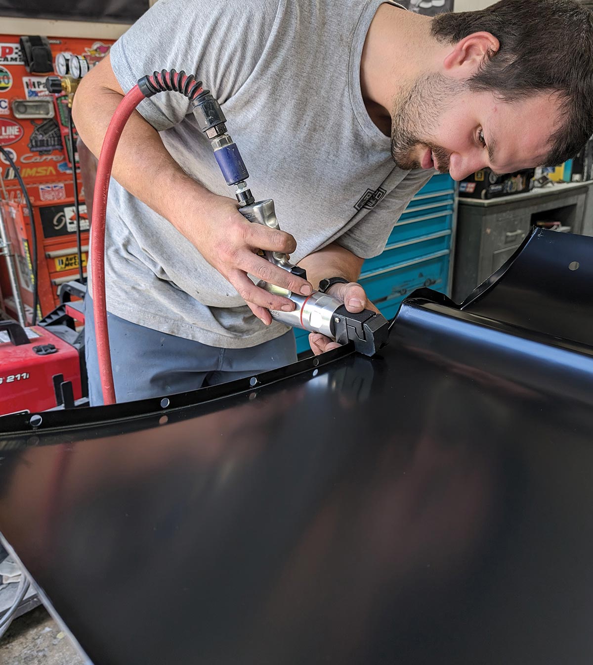 Technician grinding welds on 1966 Chevy truck door black outer skin edge