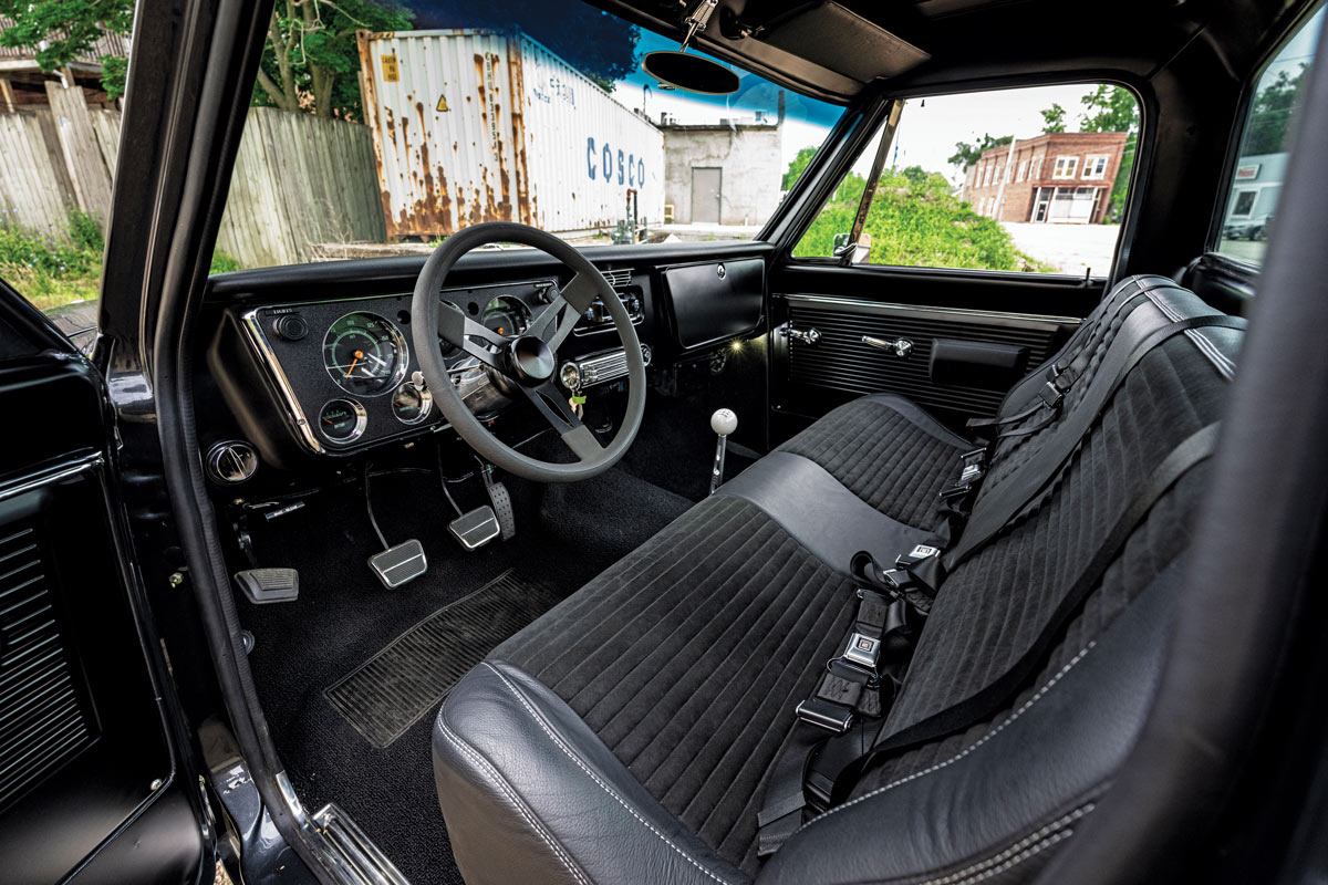 1969 Chevy C10 interior with black bench seats, retro steering wheel, and modern gauges