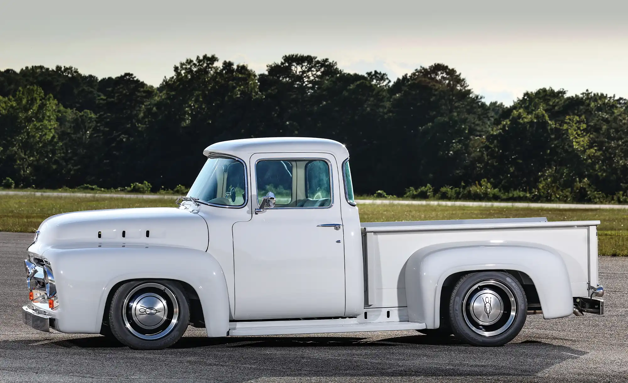 1956 Ford F-100 side profile showcasing smooth body lines, step-side bed, and lowered suspension