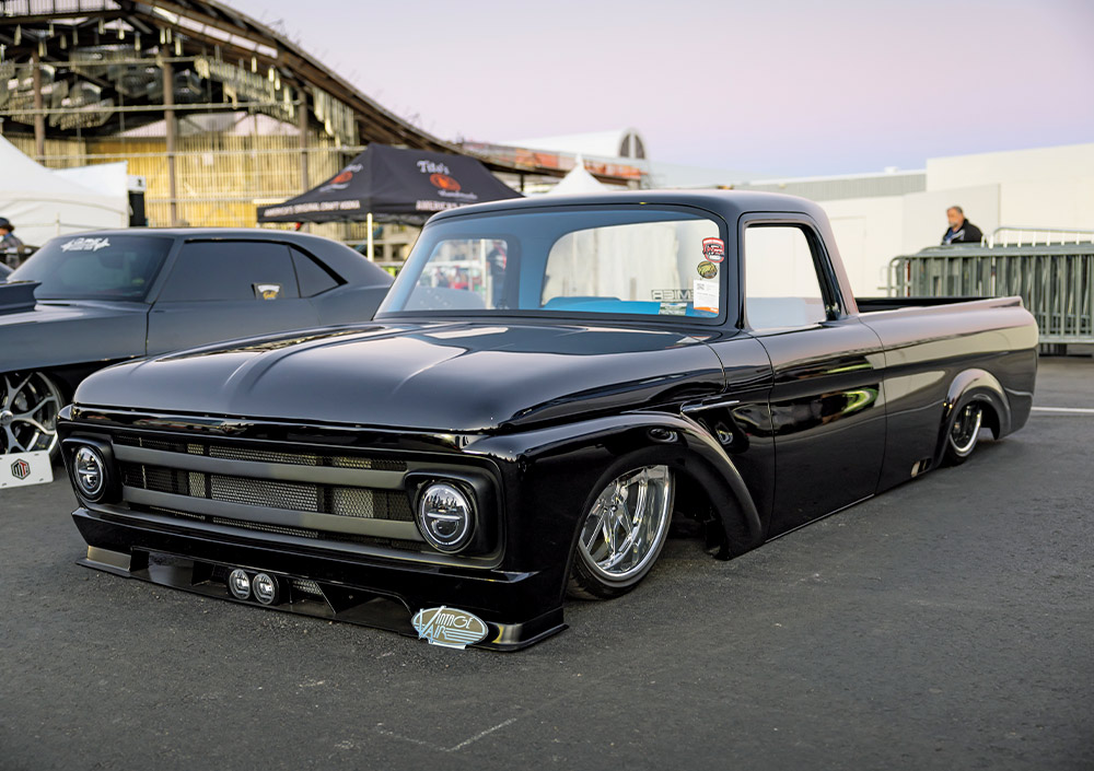 black slammed Ford F100 with aggressive front splitter and polished wheels at SEMA 2024
