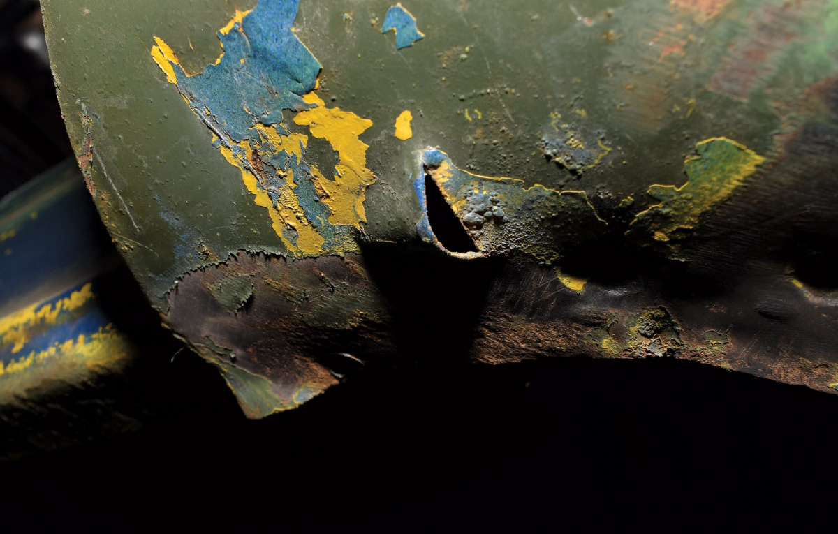 Rust holes and peeling paint exposing underlying metal damage