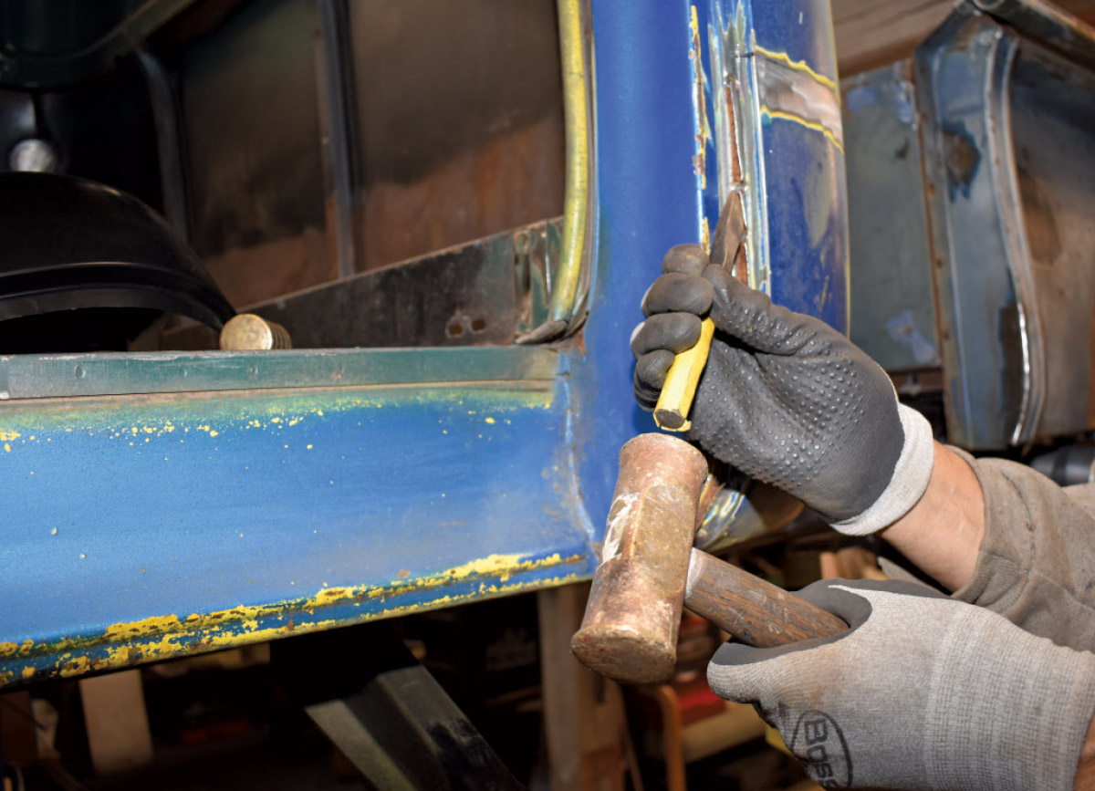Chiseling away rusted metal from the truck’s door frame for panel replacement
