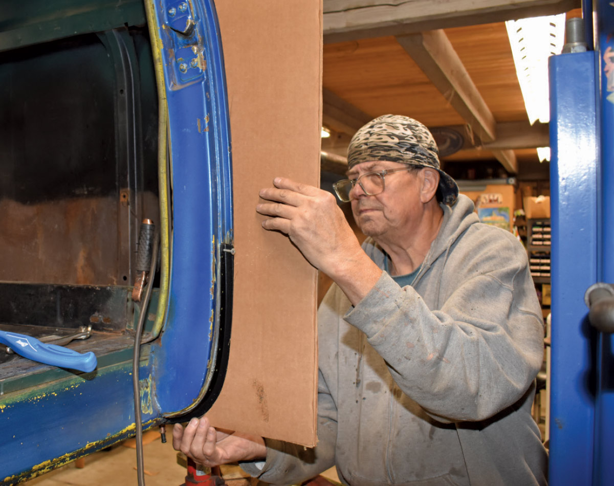 Aligning a cardboard template against the truck cab for precise metal fabrication