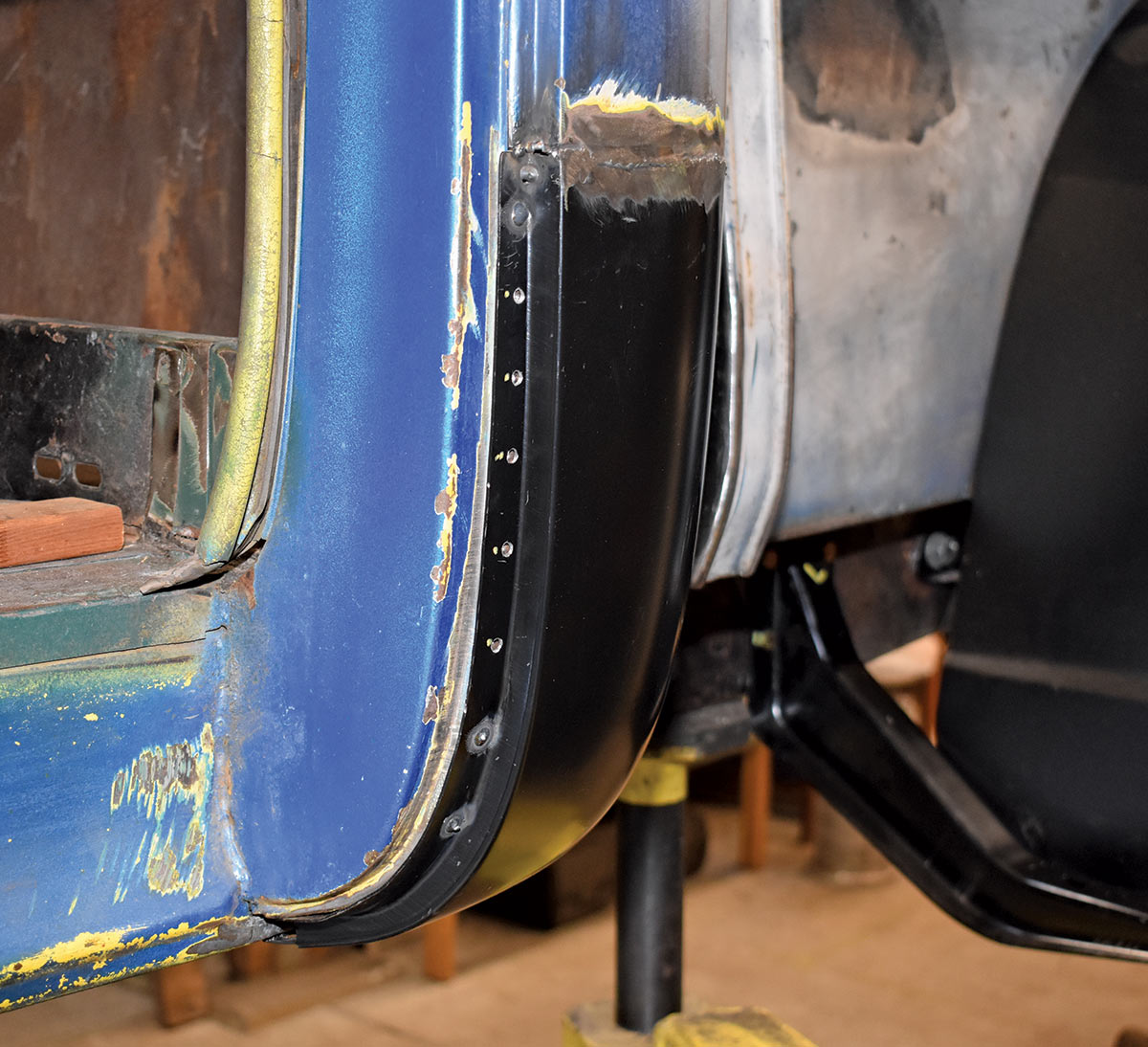 Freshly installed lower door pillar patch panel with spot welds along the seam