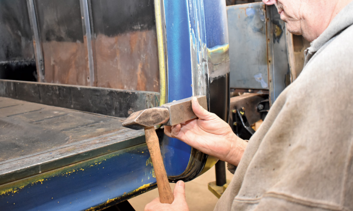 Metalworking hammer and dolly being used to refine the door pillar shape