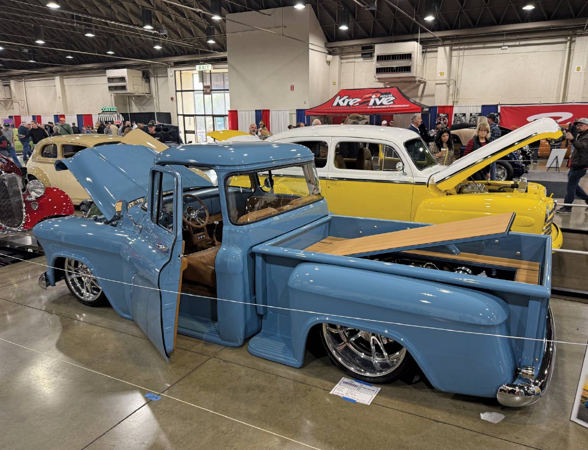 side view of blue truck with hood, trunk, and doors open